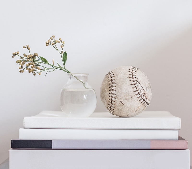 Home decor of vase and baseball on books
